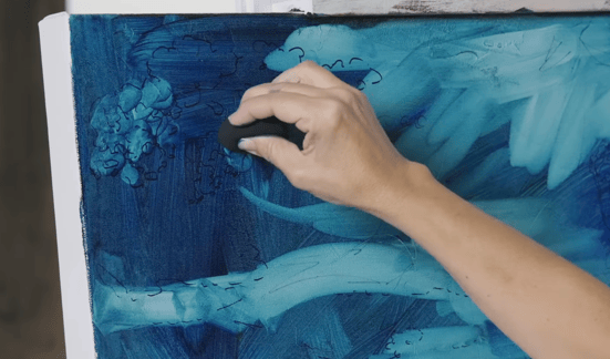 Hand subtracting blue oil paing from canvas